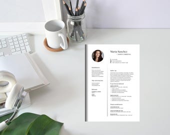 Puede incluir: Un currículum vitae con el nombre "Maria Sánchez" se muestra en un escritorio blanco. Una taza blanca, lápices en un tarro de cristal, un teclado, auriculares y un cuaderno también están en el escritorio. El currículum está en español.