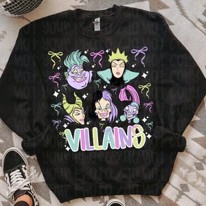 May include: Black sweatshirt with a vibrant graphic of Disney villains such as Ursula and Maleficent. The word "VILLAINS" is written in a colourful font. The design is embellished with bows and stars.