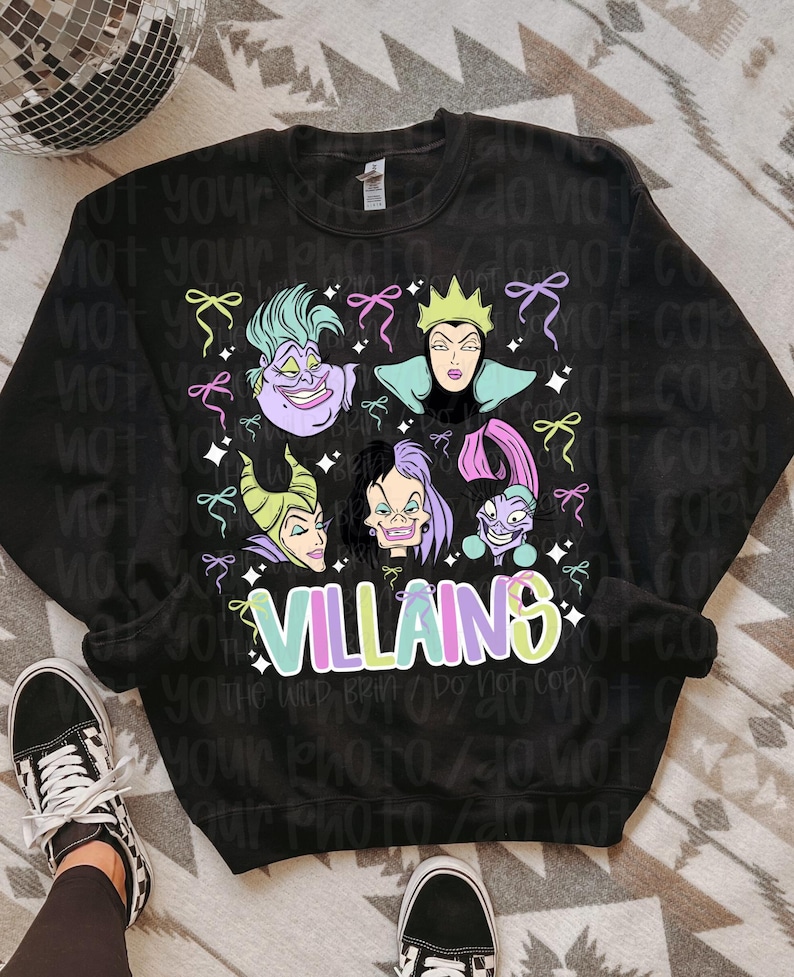 May include: Black sweatshirt with a vibrant graphic of Disney villains such as Ursula and Maleficent. The word "VILLAINS" is written in a colourful font. The design is embellished with bows and stars.