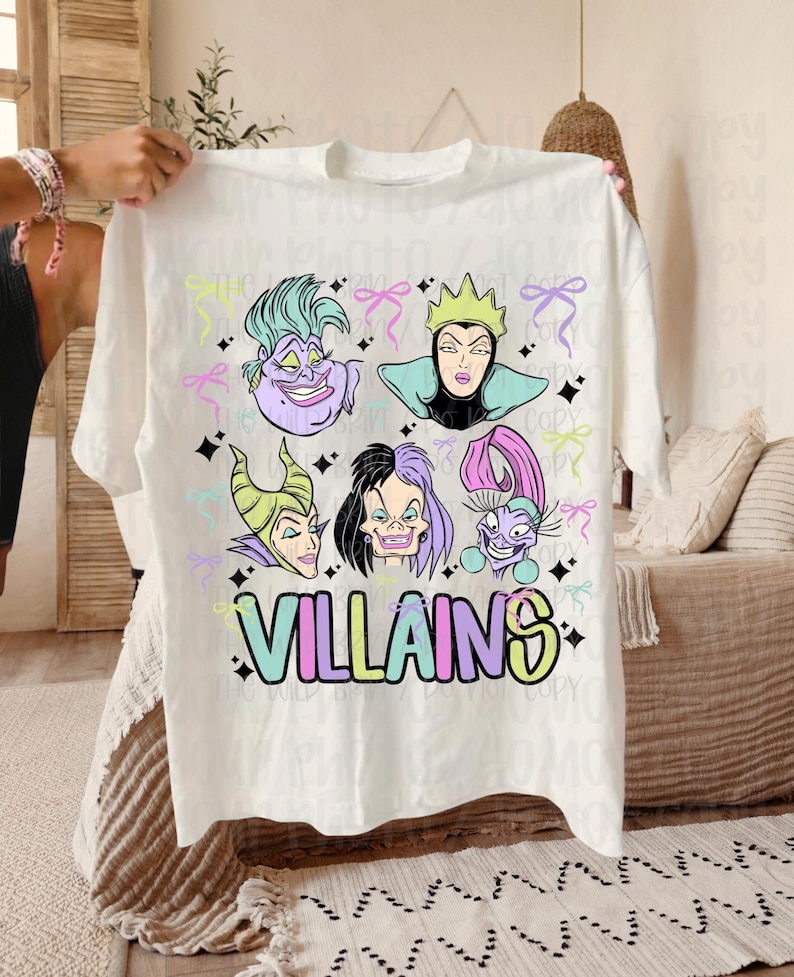 May include: White t-shirt with cartoon illustrations of six villains with colourful hair and makeup. The word "VILLAINS" is printed in pastel colours below the characters. Pastel bows and stars are scattered around the design.