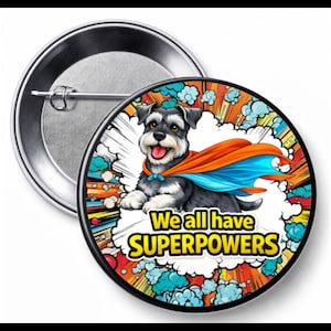 May include: A round button with a cartoon illustration of a Schnauzer dog wearing a superhero cape. The button has the text "We all have SUPERPOWERS" in yellow and white. The background has comic book style elements.