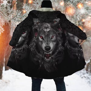 May include: Black hooded cloak featuring a detailed wolf design with red eyes and snarling teeth. The cloak has a sherpa lining and a decorative pattern on the shoulders. The wolf graphic is centered on the back of the cloak.