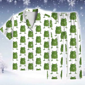 Può includere: Set pigiama bianco con un motivo ripetuto di rane verdi dei cartoni animati. Il set comprende una camicia a maniche corte con bottoni e pantaloni abbinati. Le rane hanno grandi occhi.