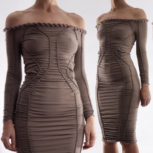 May include: A long-sleeved, off-the-shoulder dress in a light brown colour with a gathered, ruched design. The dress has a fitted silhouette and a midi length.