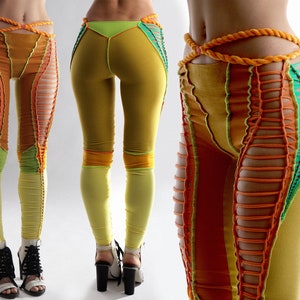 Puede incluir: Leggings amarillas, naranjas y verdes con un diseño de crochet. Las leggings tienen cintura alta y están hechas de un material elástico.