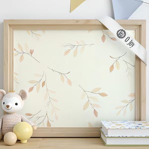 Puede incluir: Una impresión enmarcada con un fondo beige claro que presenta un patrón repetido de delicadas ramas con hojas de color melocotón y marrón. Una cinta blanca con el texto "O Joy" está colocada sobre el marco. Un peluche y dos libros están en primer plano.