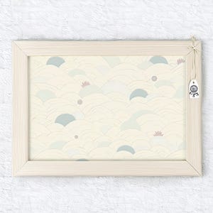 May include: A framed print featuring a repeating pattern of soft, undulating shapes in cream, blue, and pink. The artwork is enclosed in a light-colored wooden frame, with a small tag attached to the frame.