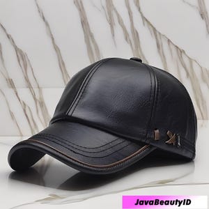 Könnte beinhalten: Schwarze Baseballkappe aus Leder mit gebogenem Schirm und dekorativen Nähten. Die Kappe hat einen braunen Besatz und Metallakzente an der Seite. Klassisches Design, geeignet für den täglichen Gebrauch.