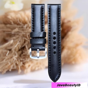 May include: Two black leather watch straps with silver-colored buckles. The straps are made of smooth leather and have stitched edges. The watch straps are designed to attach to a watch face.