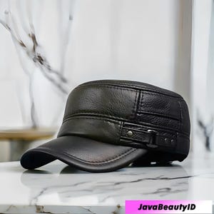 May include: A black leather military-style cap with a short peak. The cap has a structured crown with stitched detailing and a buckle fastening on the side. The text "JavaBeautyID" is visible at the bottom.