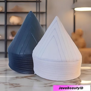 May include: Two cone-shaped hats, one navy blue and one white, are displayed. The hats have a stitched design and a rounded base. The hats are sitting on a marble surface. The text "JavaBeautyID" is at the bottom of the image.