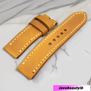Puede incluir: Una correa de reloj de cuero marrón con costuras blancas. La correa tiene múltiples agujeros para ajustar y una hebilla. La correa del reloj está hecha de un material duradero y está diseñada para un uso diario cómodo.