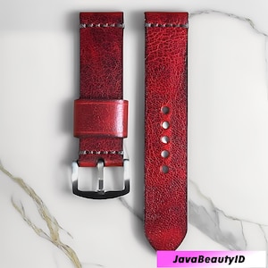 May include: Two-piece watch strap in a distressed red leather. The strap features silver-tone hardware, visible stitching, and multiple adjustment holes. The leather has a textured appearance.