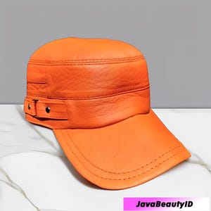 K&ouml;nnte beinhalten: Orangefarbene Lederkappe mit flachem Schirm und strukturierter Krone. Die Kappe hat ein Banddetail mit einer Schnalle an der Seite. Die N&auml;hte sind entlang der N&auml;hte und des Schirms sichtbar. Die Kappe hat eine leuchtende Farbe.