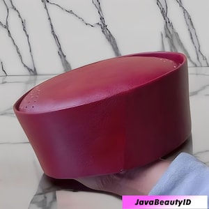 May include: A burgundy-colored hat with a rounded top and a slightly angled brim. The hat has a smooth, matte finish and appears to be made of a soft material. The text "JavaBeautyID" is visible in the bottom right corner.