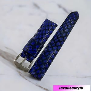 Puede incluir: Correa de reloj de dos piezas en un tono azul vibrante. La correa presenta un patrón texturizado en forma de escamas y una hebilla plateada. La correa del reloj está diseñada para fijarse a una esfera de reloj. La imagen incluye el texto "JavaBeautyID".
