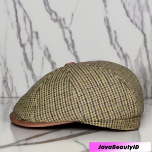 Puede incluir: Gorra newsboy de tweed en tonos verdes, marrones y negros, con visera marrón. La gorra presenta un patrón de cuadros clásico y una corona redondeada. La visera es de color marrón liso. Fondo de mármol.