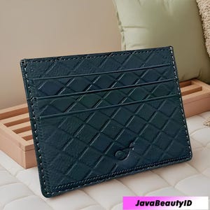 May include: Dark teal card holder with a diamond pattern and white stitching. The card holder has three card slots and a small logo. The text "JavaBeautyID" is displayed at the bottom.