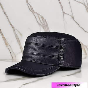 May include: A navy blue leather cap with a flat brim and a structured crown. The cap features horizontal stitched details and two silver-colored buttons on the side. The text "JavaBeautyID" is visible at the bottom.