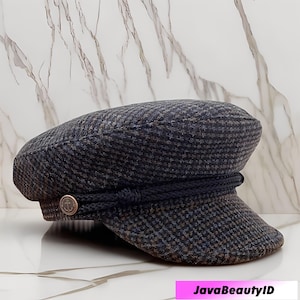 Peut inclure: Casquette de marin à carreaux bleu marine et marron, avec un détail de corde bleu foncé et un bouton ancre doré. La casquette a une couronne arrondie et un bord court et rigide. Le chapeau est en tissu texturé.