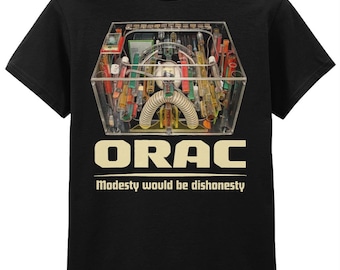 Könnte beinhalten: Schwarzes T-Shirt mit einer komplexen, farbenfrohen Grafik einer Maschine oder eines Geräts in einer transparenten Box. Das Wort "ORAC" steht über dem Satz "Modesty would be dishonesty" in einem beigen Farbton.