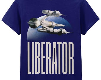 Op de afbeelding: Marineblauw T-shirt met een ruimteschipontwerp en het woord "LIBERATOR" in grote witte letters. Het ruimteschip is lichtgrijs en wit, tegen een blauw-witte planeetachtergrond.