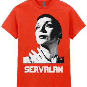May include: A bright red t-shirt featuring a black and white portrait of a woman with the name "SERVALAN" printed in white block letters below the portrait. The t-shirt is made of a soft material.