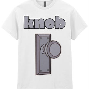 Op de afbeelding: Een wit T-shirt met korte mouwen en een afbeelding van een grijze deurknop met een rechthoekige achterplaat in het midden op de borst. Boven de afbeelding van de deurknop staat het woord knob in dikke, grijze, schreefloze hoofdletters.