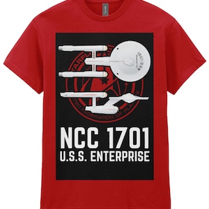 Può includere: Maglietta rossa con una grafica in bianco e nero della nave spaziale USS Enterprise di Star Trek. La grafica include il numero di registrazione della nave, NCC 1701, e le parole "U.S.S. ENTERPRISE".