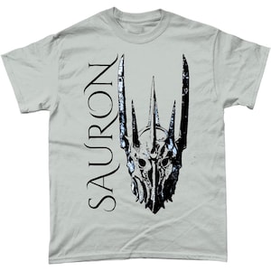 May include: A light grey t-shirt featuring a black and white graphic of the Lord of the Rings character Sauron's crown. The word "SAURON" is printed vertically on the left side of the shirt.