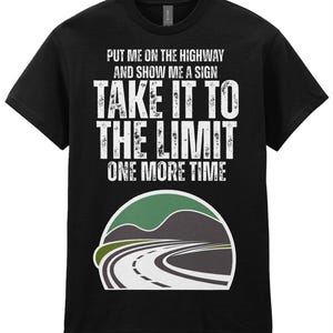 May include: A black short-sleeved t-shirt featuring white distressed text that reads: PUT ME ON THE HIGHWAY AND SHOW ME A SIGN TAKE IT TO THE LIMIT ONE MORE TIME. Below the text is a graphic of a road winding through hills in green and grey.