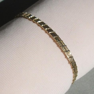 May include: A gold-tone chain bracelet with a textured design.