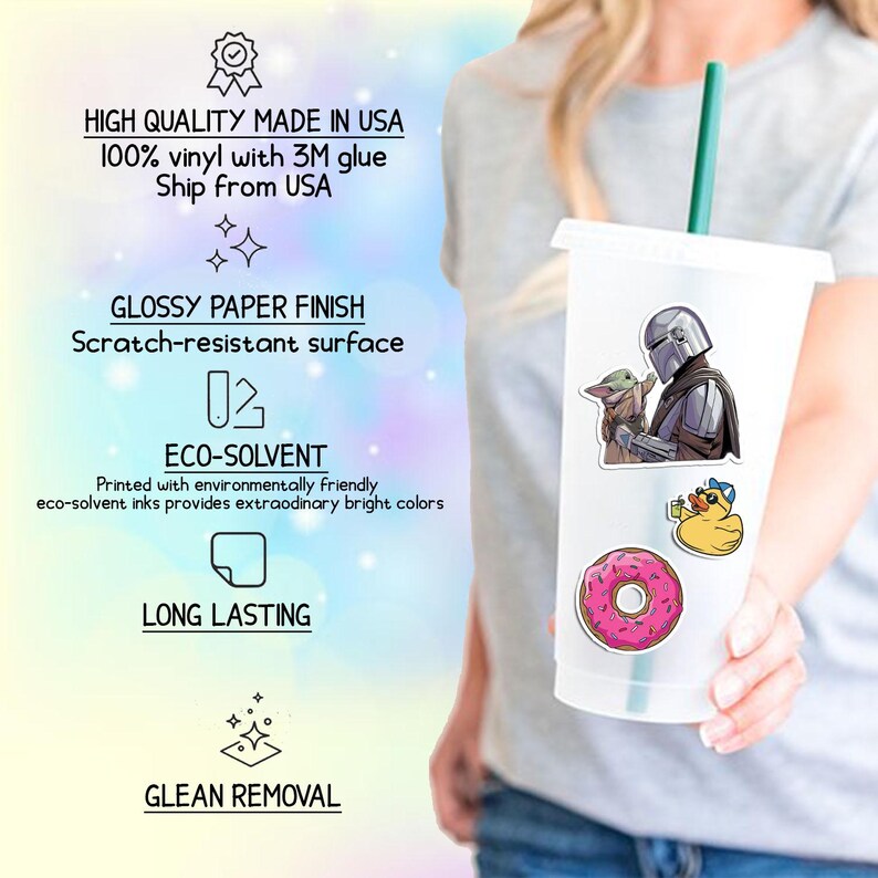May include: A clear plastic tumbler with a green straw, decorated with stickers of a character in armor with a baby, a yellow duck with sunglasses, and a pink donut. The tumbler is held by a person.