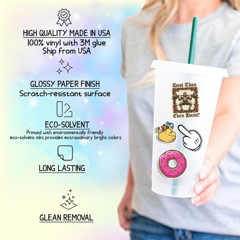 May include: A clear plastic tumbler with a green straw, decorated with various stickers. Stickers include a cartoon duck, a pointing hand, a pink donut, and a weightlifting robot with the text "Dost Thou Even Hoist?"