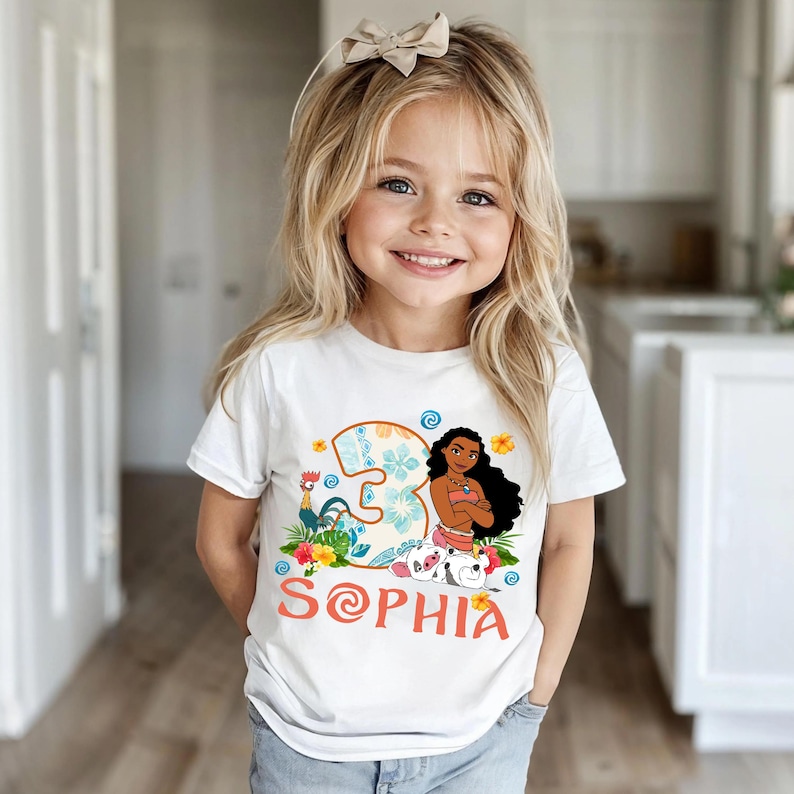 Puede incluir: Una camiseta blanca con un gr&aacute;fico colorido de un personaje de dibujos animados, un gallo y el n&uacute;mero "3" con detalles florales. El nombre "Sophia" est&aacute; impreso en naranja debajo. La camiseta la lleva una ni&ntilde;a peque&ntilde;a.