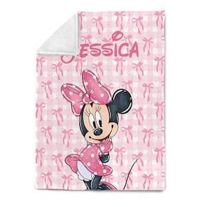 May include: A pink and white blanket featuring a Minnie Mouse cartoon character. The blanket has a repeating pattern of pink bows and a gingham background. The name "ESSICA" is printed in pink on the blanket.