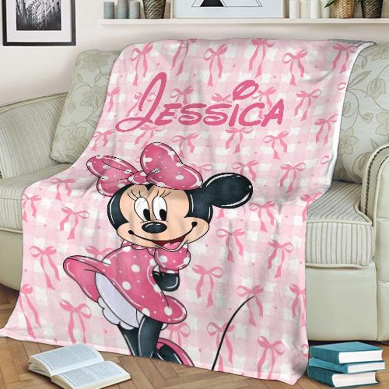 May include: Pink and white Minnie Mouse blanket with the name "Jessica" in pink script. The blanket features a pattern of bows and a large Minnie Mouse graphic in a pink polka dot dress.