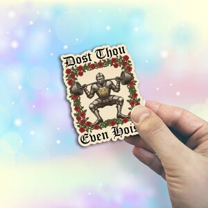 May include: A sticker featuring a knight lifting weights, surrounded by red roses. The sticker has the text "Dost Thou Even Hoist" in an ornate font. The knight is wearing silver armor and lifting a barbell.
