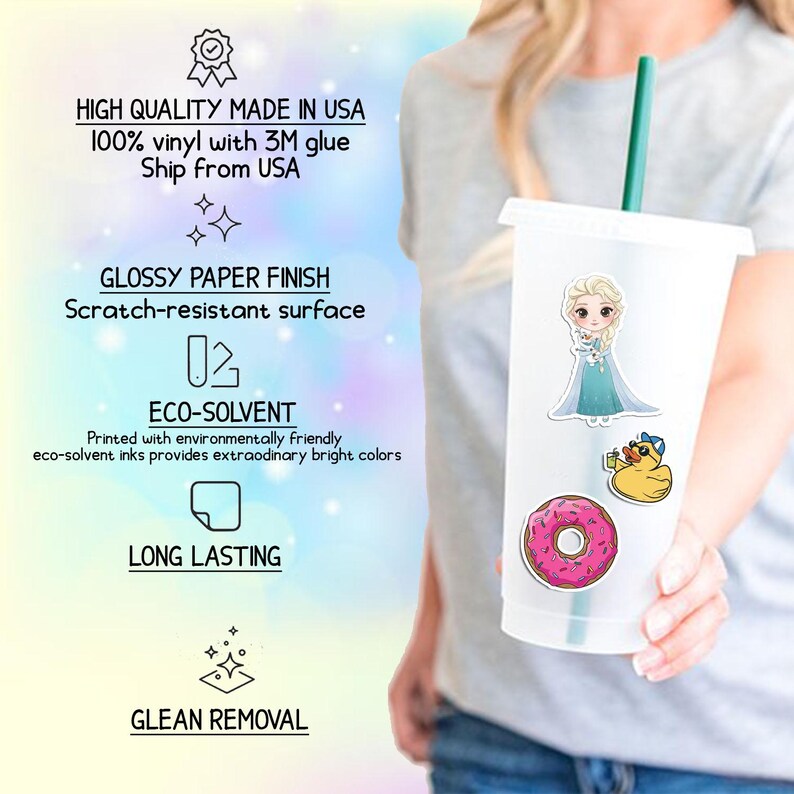 May include: A clear plastic tumbler with a green straw, decorated with stickers of a cartoon princess, a rubber duck, and a pink donut. The tumbler has the following text: "HIGH QUALITY MADE IN USA", "GLOSSY PAPER FINISH", "ECO-SOLVENT", "LONG LASTING", and "GLEAN REMOVAL".
