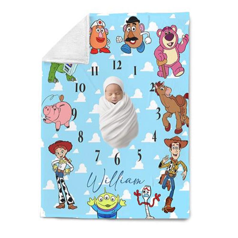 May include: A baby blanket featuring a light blue background with cartoon characters and a clock design. The blanket has a white border and the name "William" in cursive. The blanket is decorated with characters from the movie Toy Story.