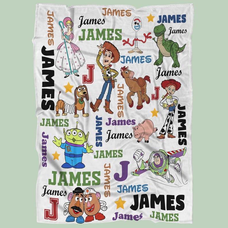 May include: White blanket featuring various Toy Story characters, including Woody, Buzz Lightyear, and Rex. The blanket has the name "James" printed repeatedly in different colors and fonts, along with the letter "J" in a red box.
