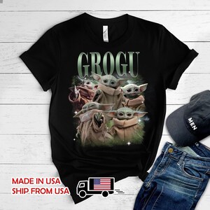 May include: A black short-sleeve t-shirt featuring a graphic print of multiple Grogu characters in tan robes. The text GROGU is printed in a large, light green font above the characters. The design includes subtle lightning and star accents.