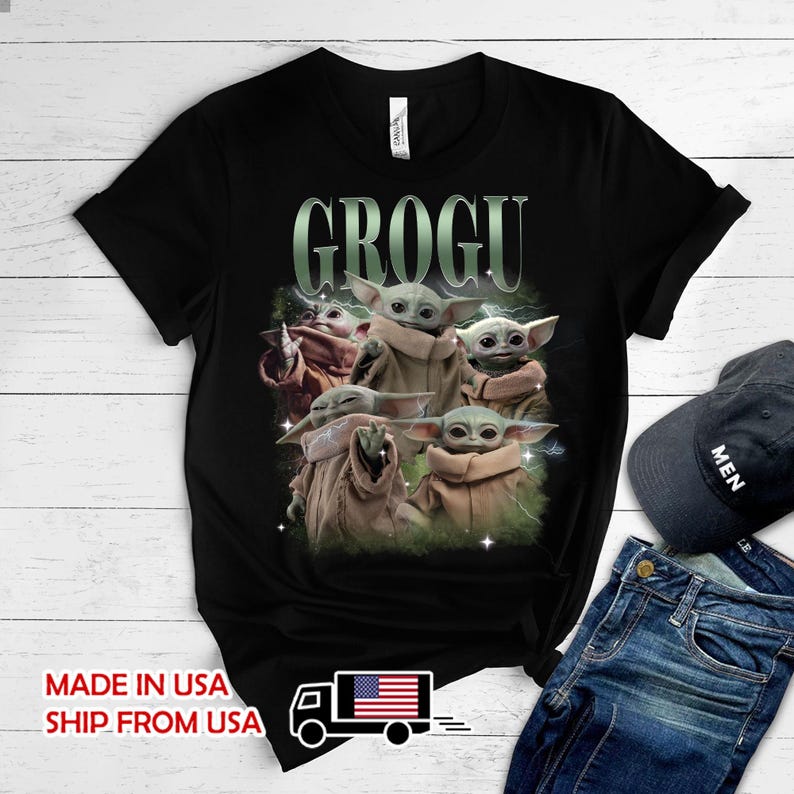 May include: A black short-sleeve t-shirt featuring a graphic print of multiple Grogu characters in tan robes. The text GROGU is printed in a large, light green font above the characters. The design includes subtle lightning and star accents.