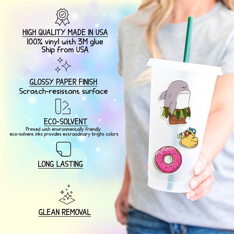 May include: A clear plastic tumbler with a green straw, decorated with stickers. The stickers include a cartoon shark, a yellow duck with sunglasses, and a pink donut. The tumbler is held by a person.