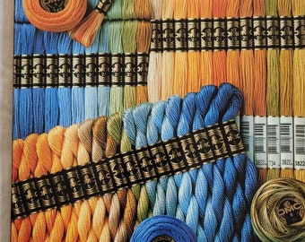May include: A display of DMC embroidery floss and pearl cotton threads in various colors, including blues, oranges, and greens. The packaging features the DMC logo and product information, including "MOULINÉ SPÉCIAL 25" and "COTON PERLÉ". The image showcases different thread sizes.