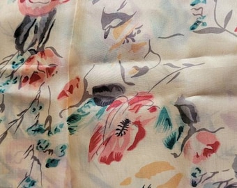 May include: Cream-colored fabric with a floral pattern. The design features large, stylized flowers in shades of red, pink, and peach, with green and gray foliage. The fabric has a soft, slightly wrinkled texture, suggesting a lightweight material.