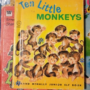 May include: A vintage children's book titled "Ten Little Monkeys" with a yellow cover and illustrations of monkeys in various poses. The book is published by Rand McNally and is part of their Junior Elf Book series.