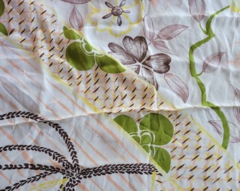 May include: A white scarf with a floral pattern in shades of brown, green, and yellow. The scarf features a repeating design of flowers, leaves, and geometric shapes, with a border of pink and brown stripes.