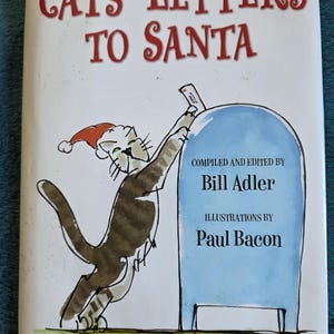 May include: A book titled Cats' Letters to Santa with a white cover featuring a cartoon illustration of a tabby cat wearing a red Santa hat, placing a letter into a light blue mailbox. The text reads Compiled and Edited by Bill Adler.