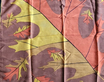 May include: A brown silk scarf with a pattern of yellow and orange leaves. The leaves are stylized and have a geometric design.